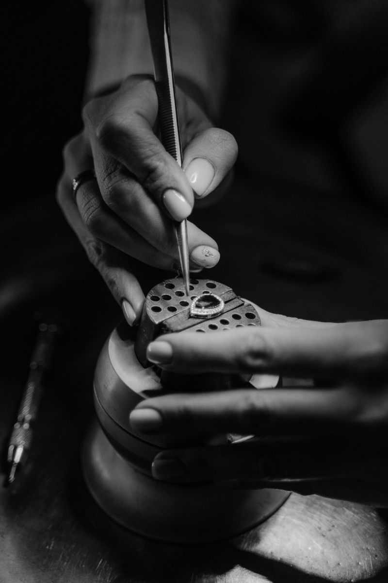 Close-up of a jeweler setting a gemstone in black and white