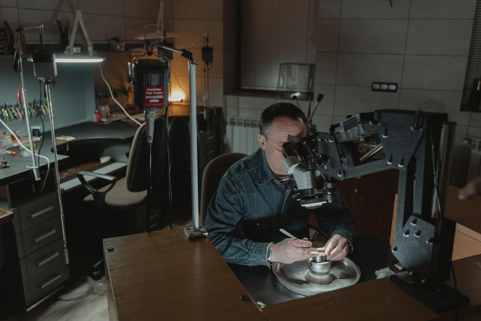 A jeweler analyzing a ring under a microscope to determine repair costs A jeweler analyzing a ring under a microscope to determine repair costs