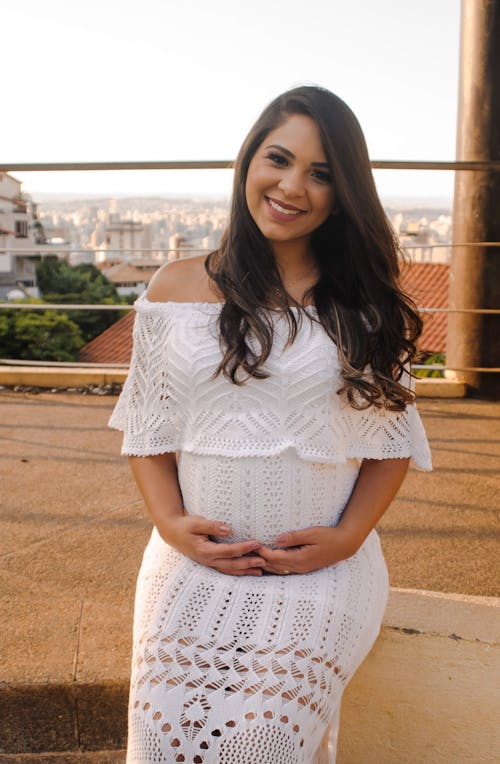 Free Cheerful ethnic pregnant woman sitting on street Stock Photo
