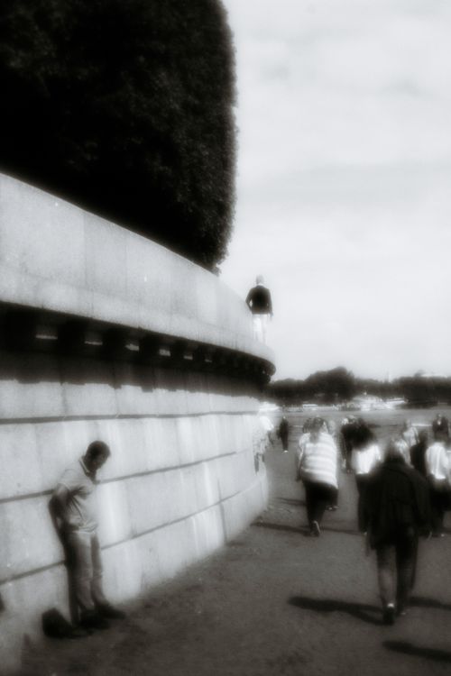 Free A nostalgic black and white street scene with people walking along a curved wall. Stock Photo