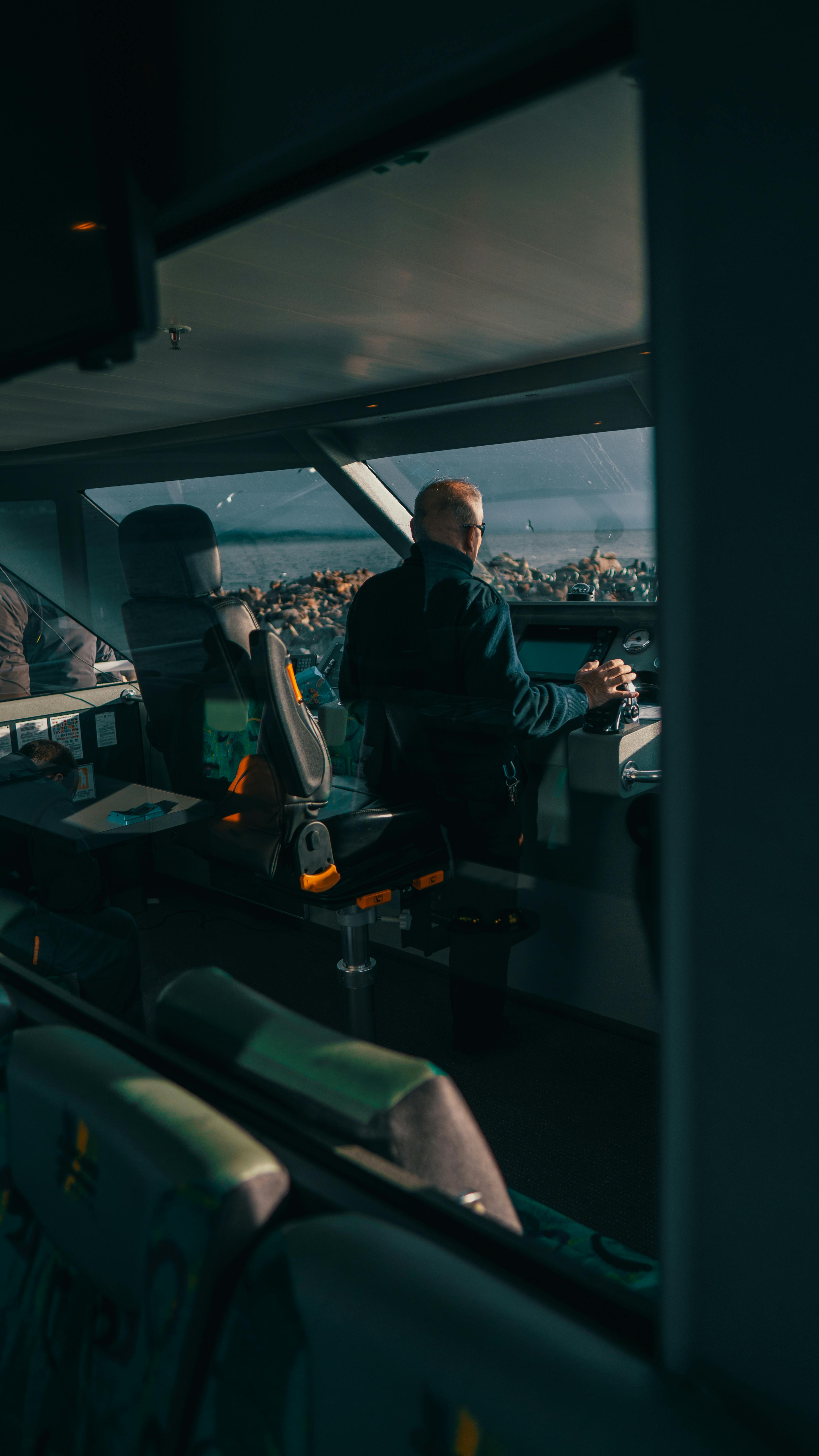 Prescription Goggle Inserts - A man steering a vessel confidently from the control room with ocean view.