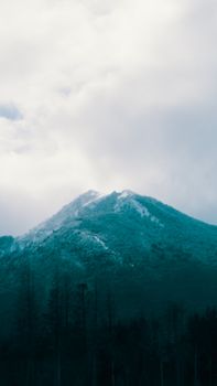 Stunning view of a snow-covered mountain peak beneath a cloudy sky, capturing the essence of nature's tranquility.