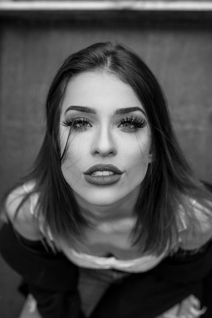 Striking black and white portrait of a young woman with a bold look, captured from a high angle.