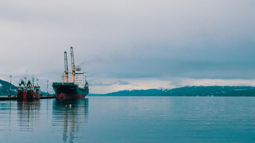 Free Calm and serene harbor with cargo ships docked, surrounded by snowy mountains. Stock Photo
