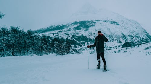 Uomo In Giacca Nera E Pantaloni Neri In Piedi Su Un Terreno Innevato