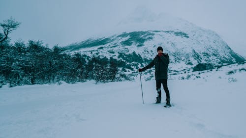 Homme En Veste Noire Et Pantalon Noir Marchant Sur Un Sol Couvert De Neige