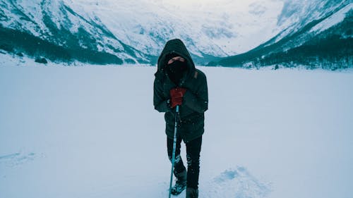 Man In Zwarte Jas En Zwarte Broek Staande Op Besneeuwde Grond