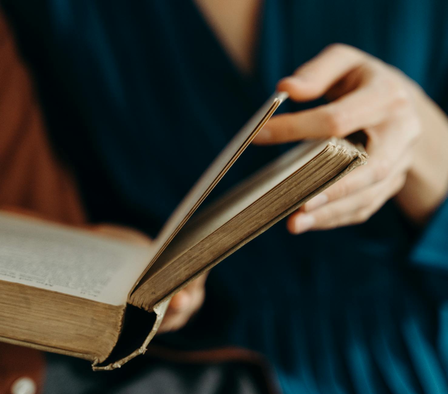 Person holding and flipping through pages of an old book.