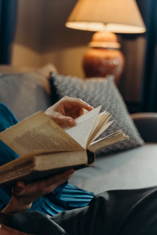 Free Close-up of a person reading a book in a cozy indoor setting with soft lighting. Stock Photo