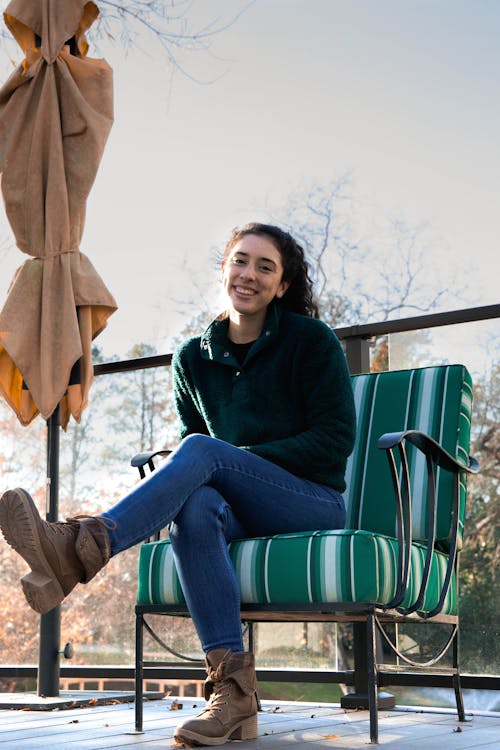 Full Shot of a Woman Smiling while Sitting on a Green Chair