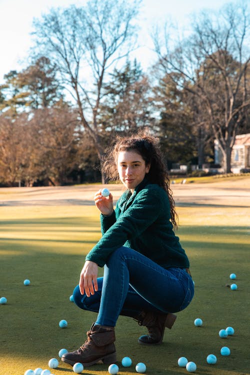 Woman in Green Sweater Holding a Golf Ball