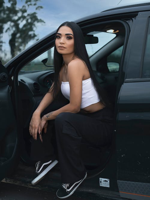 A Woman in White Tube Top Sitting in the Car's Driver Seat