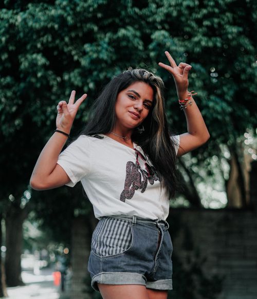 Free Young woman posing outdoors with peace signs, wearing denim shorts and smiling in Buenos Aires. Stock Photo