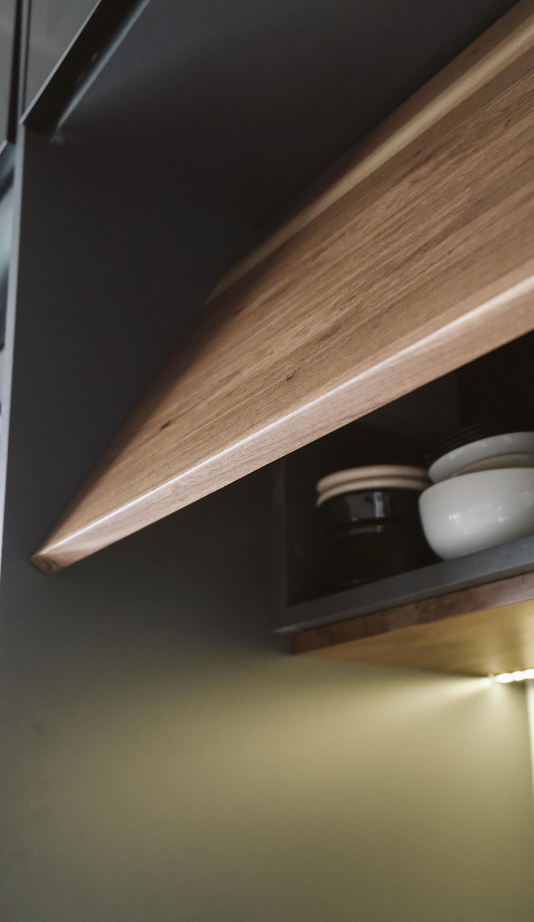 Minimalist open kitchen shelf with neatly arranged bowls and natural wooden accents