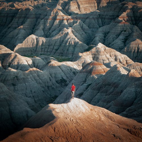 Person in Red Shirt Standing on Rock Mountain