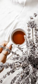 Top view of a hand holding a tea cup with lavender for a serene and calming vibe.