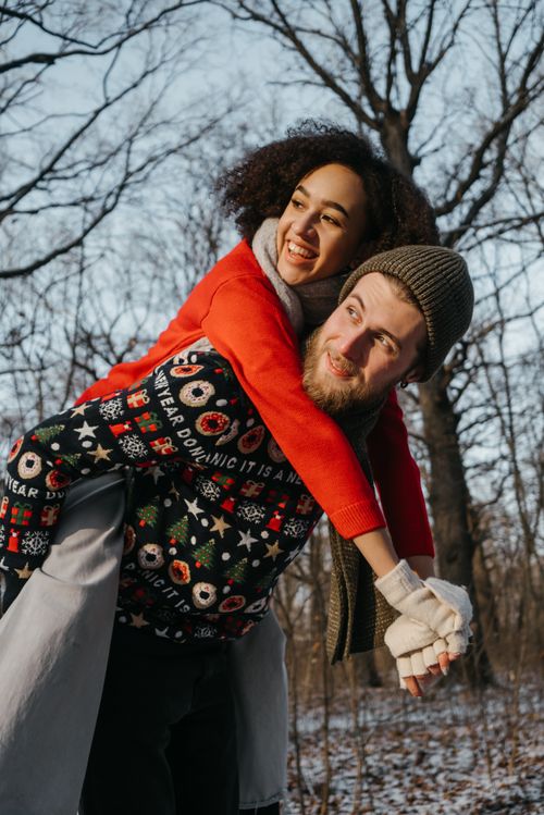 Free Happy couple enjoying a winter day outdoors, wearing festive clothing in a lively seasonal scene. Stock Photo