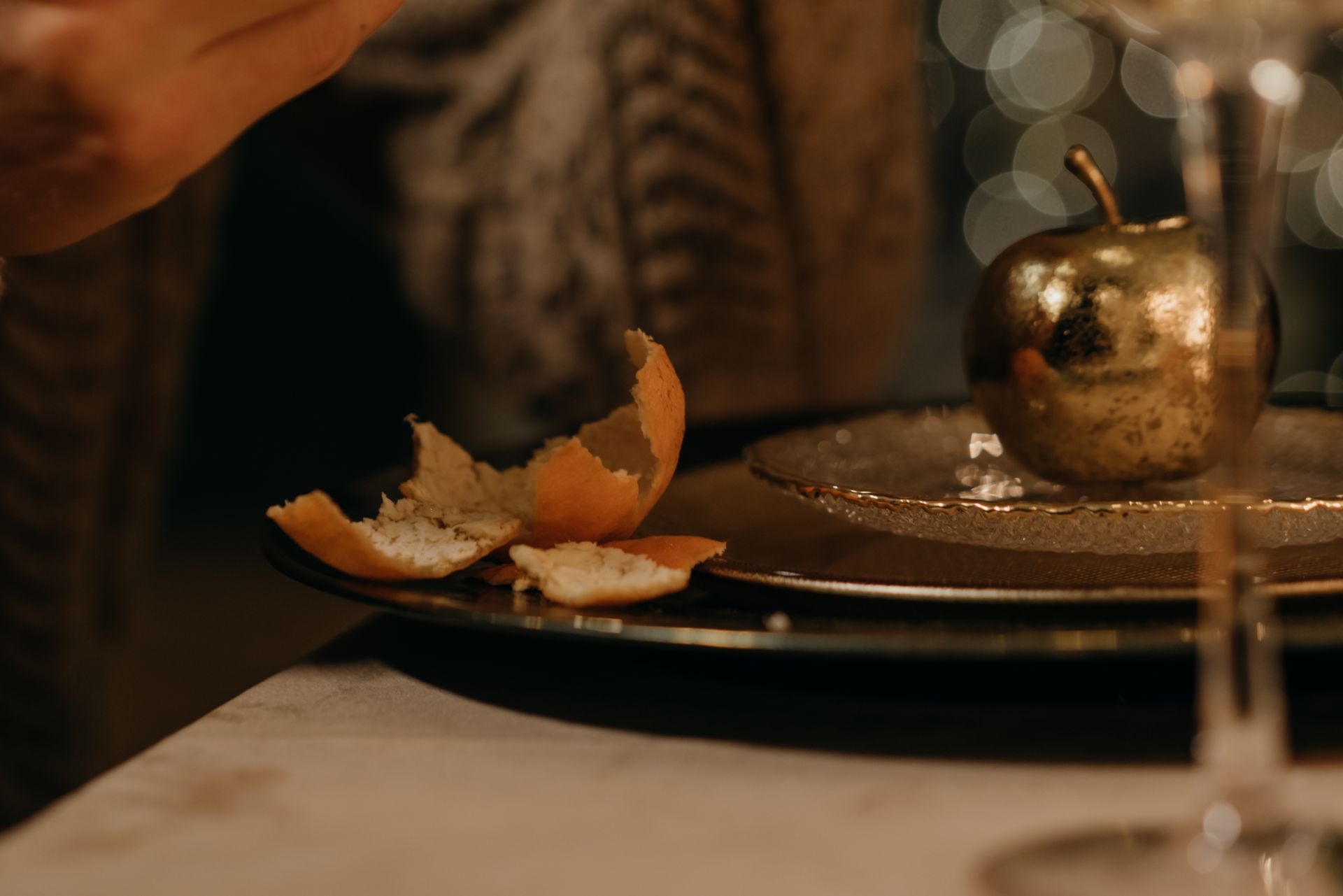 Close-up of a table setting with orange peel and a decorative golden apple, creating an elegant dining atmosphere.