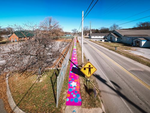 Free Empty road running through town with residential buildings and colorful graffiti on concrete wall under cloudless sky Stock Photo