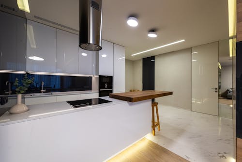 Modern kitchen interior with counter and appliances and glossy cabinets under shining lamps