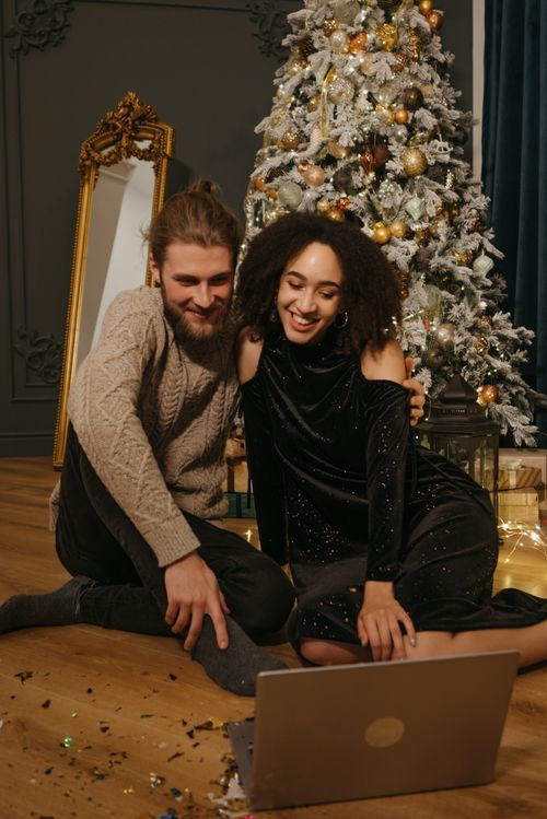 Free Smiling couple enjoying a video call by a decorated Christmas tree, celebrating festive moments indoors. Stock Photo