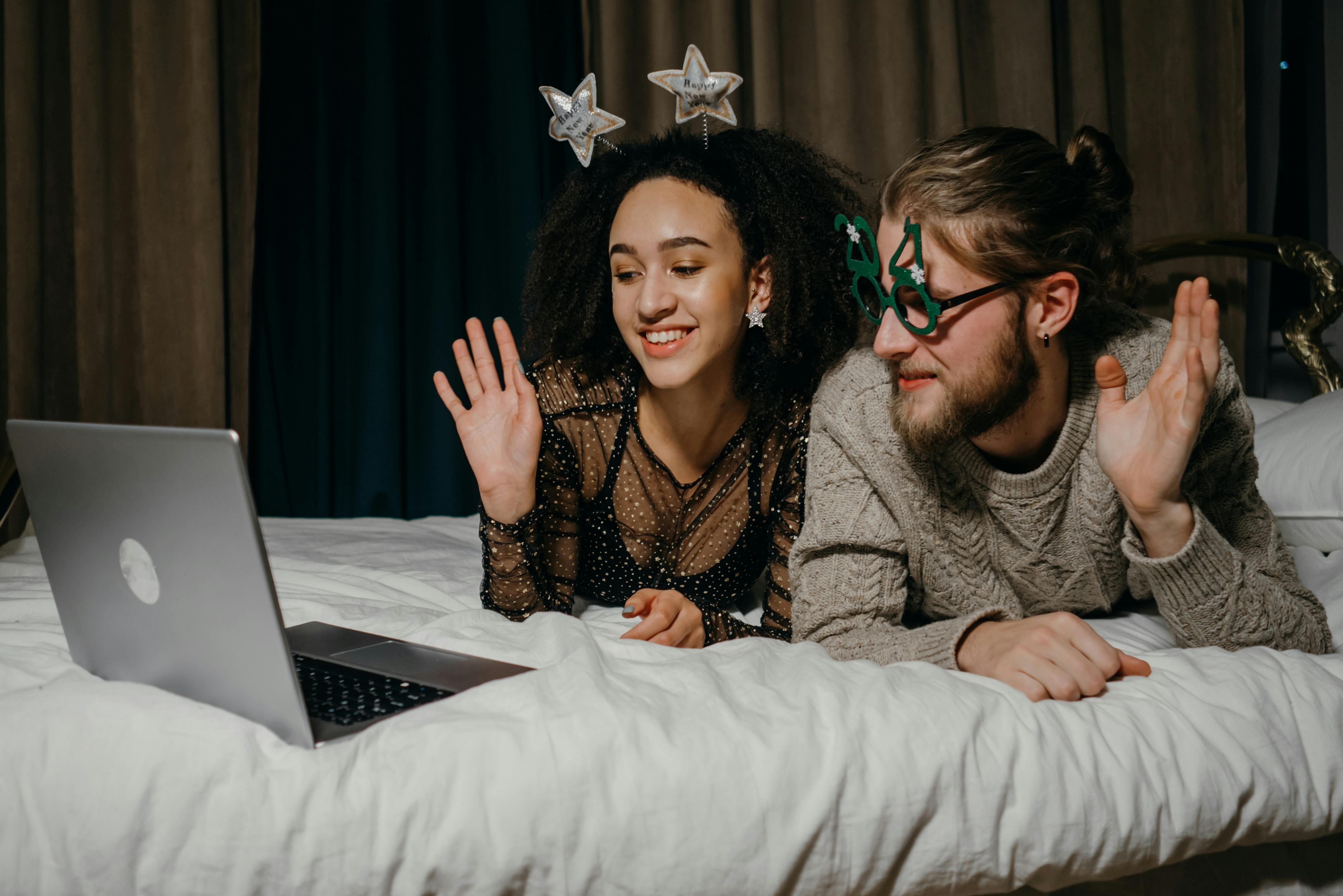 couple waving their hands on the laptop during video call