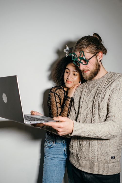 A Couple Looking at a Laptop while Sitting on the Floor · Free Stock Photo