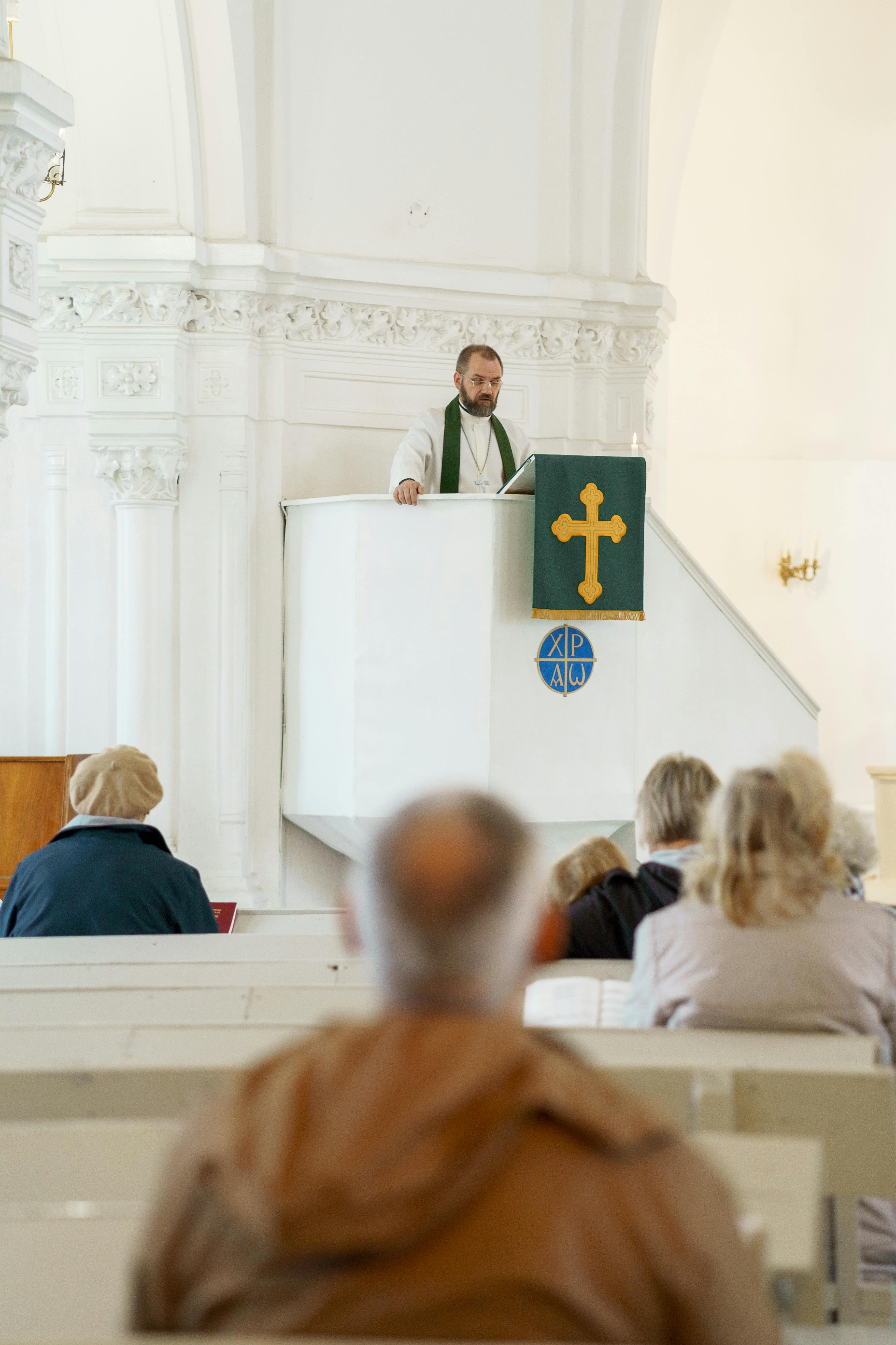 A pastor delivers a sermon to a congregation in a historic church interior.