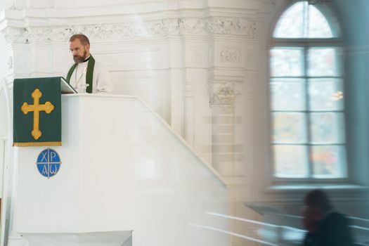 A preacher standing at a pulpit inside a historic church during a religious ceremony.