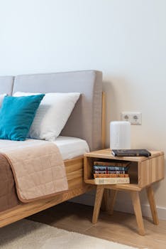 A modern bedroom setup with a comfortable bed, stylish bedside table, and stack of books for a cozy reading nook.