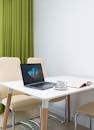 Opened laptop with book and cup of coffee placed on table in modern apartment