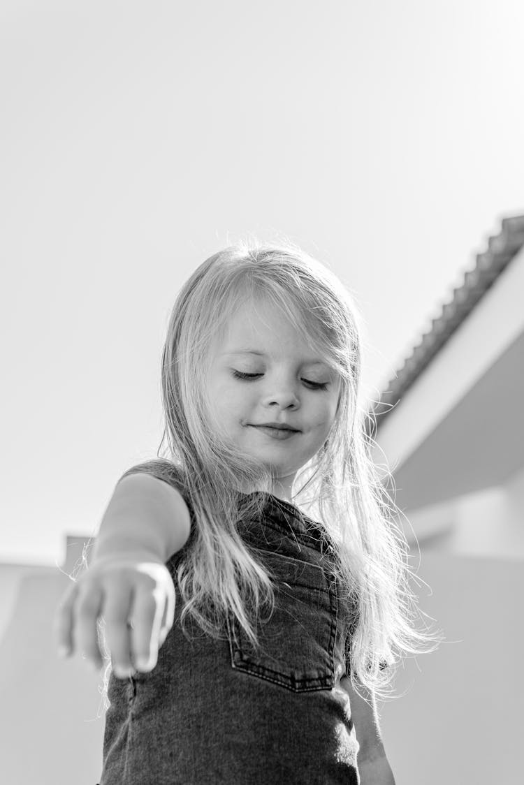 Cute Child Playing On Street Near House In Sunlight