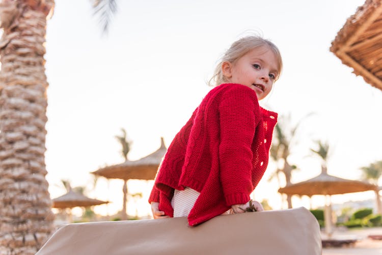 Happy Little Girl Leaning On Soft Deckchair On Tropical Beach