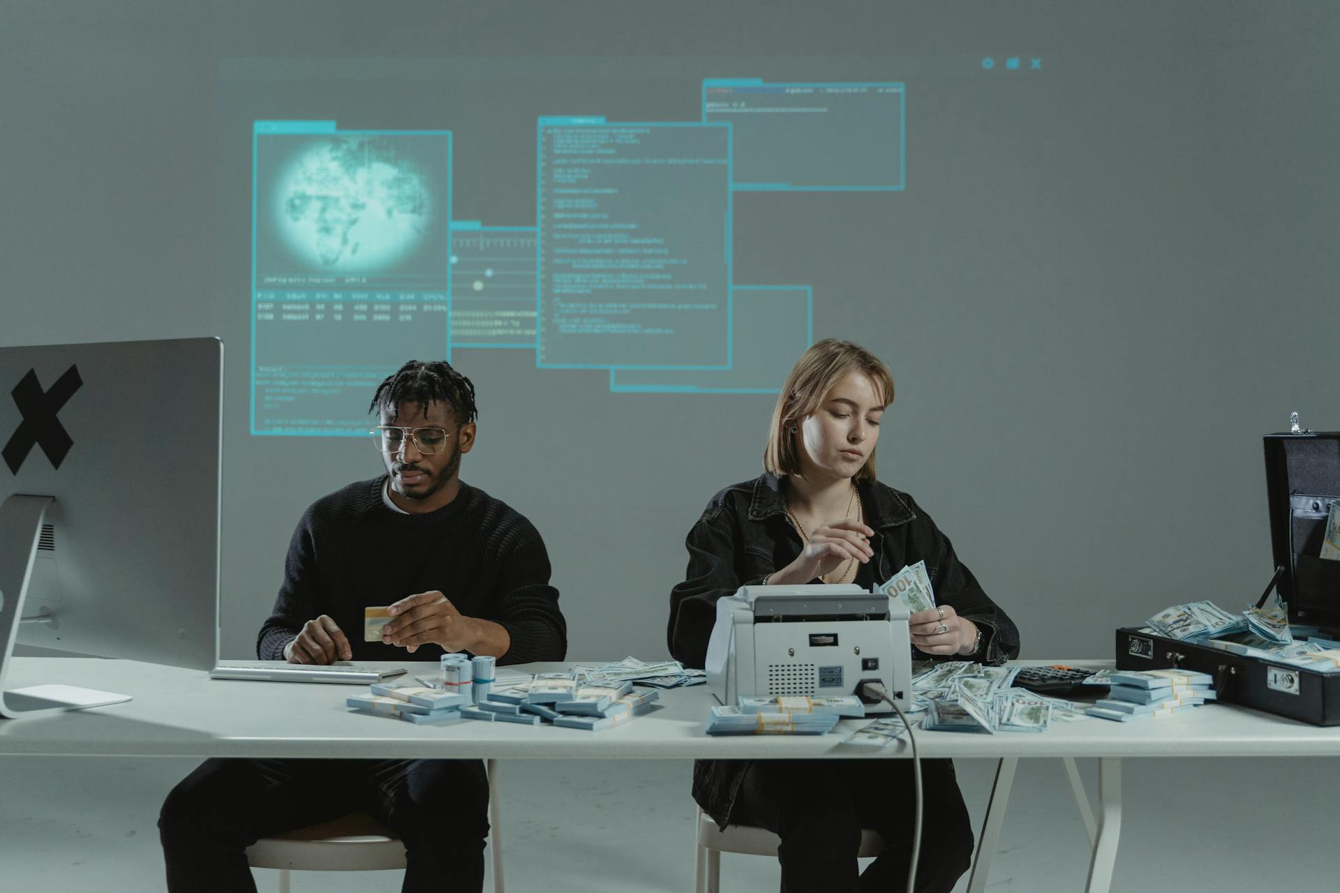 Two adults counting money in an office with a tech-themed background.