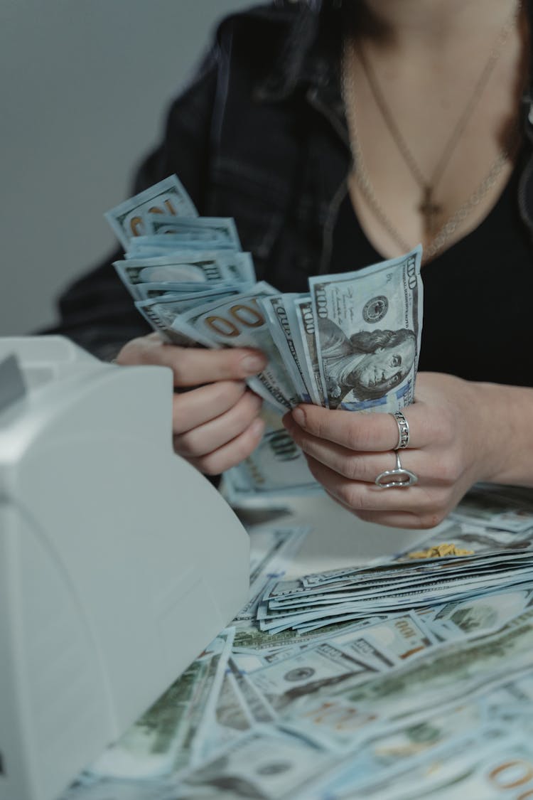 Person Counting Money On Her Hands