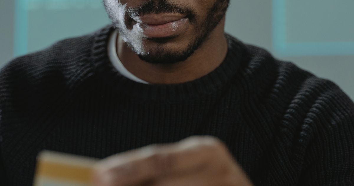 A man in eyeglasses holding a payment card.