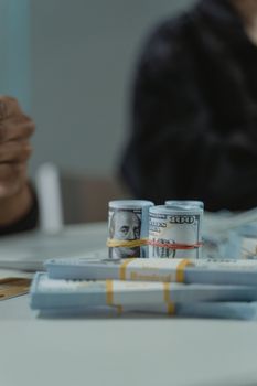 Close-up of rolled and stacked US hundred dollar bills on a table, perfect for finance themes.