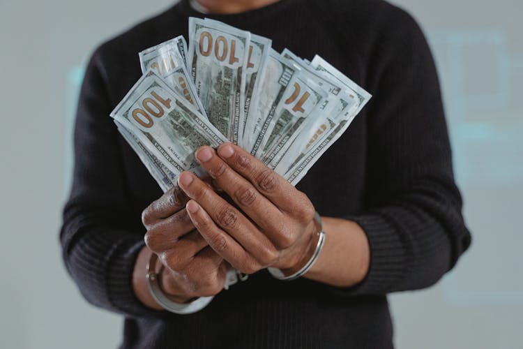 Person Holding Fan Of Dollar Bills