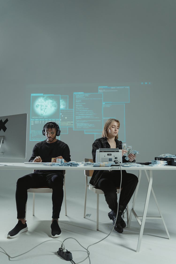 A Man And A Woman Sitting At A Table Counting Money