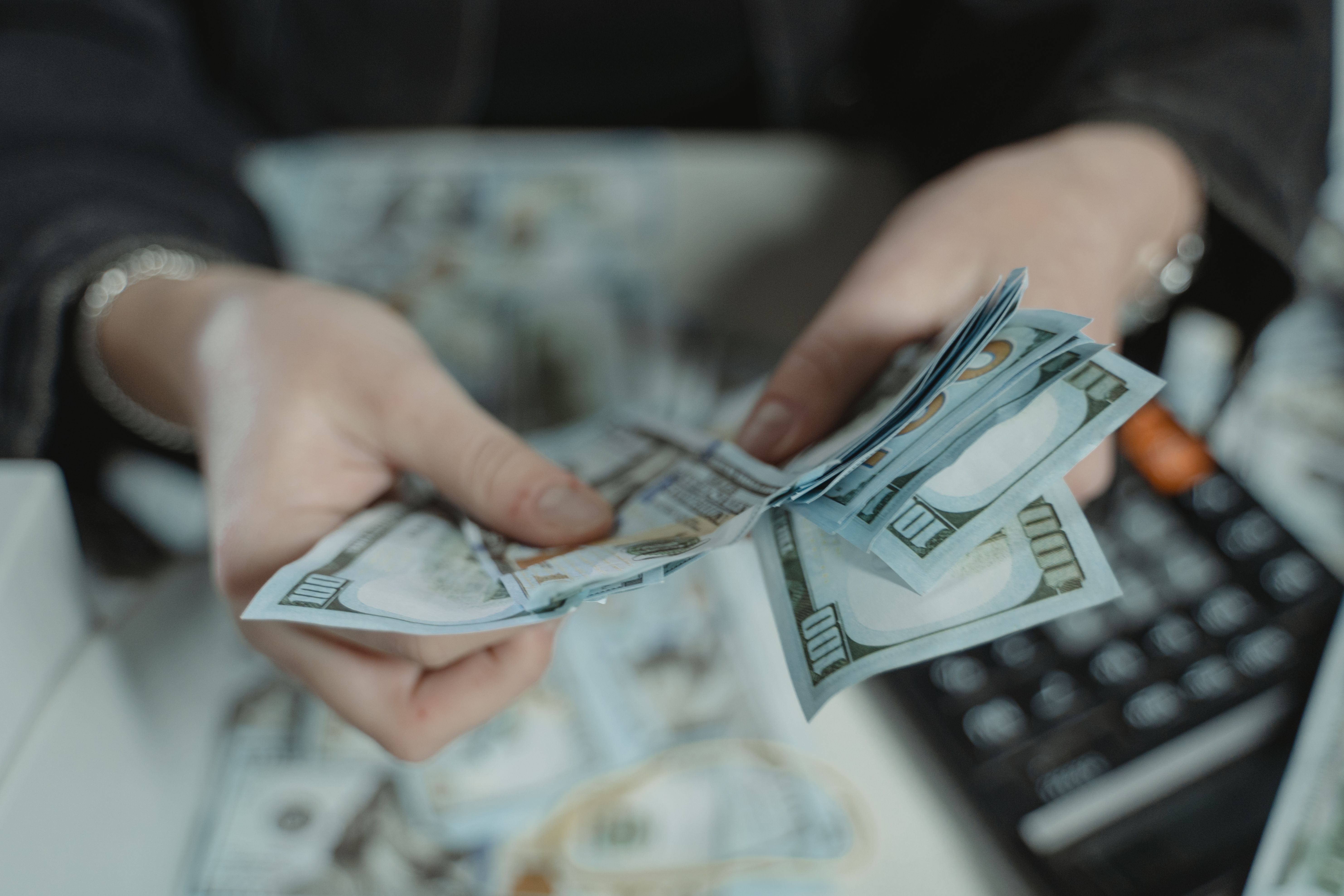a person holding a pile of cash and calculating it