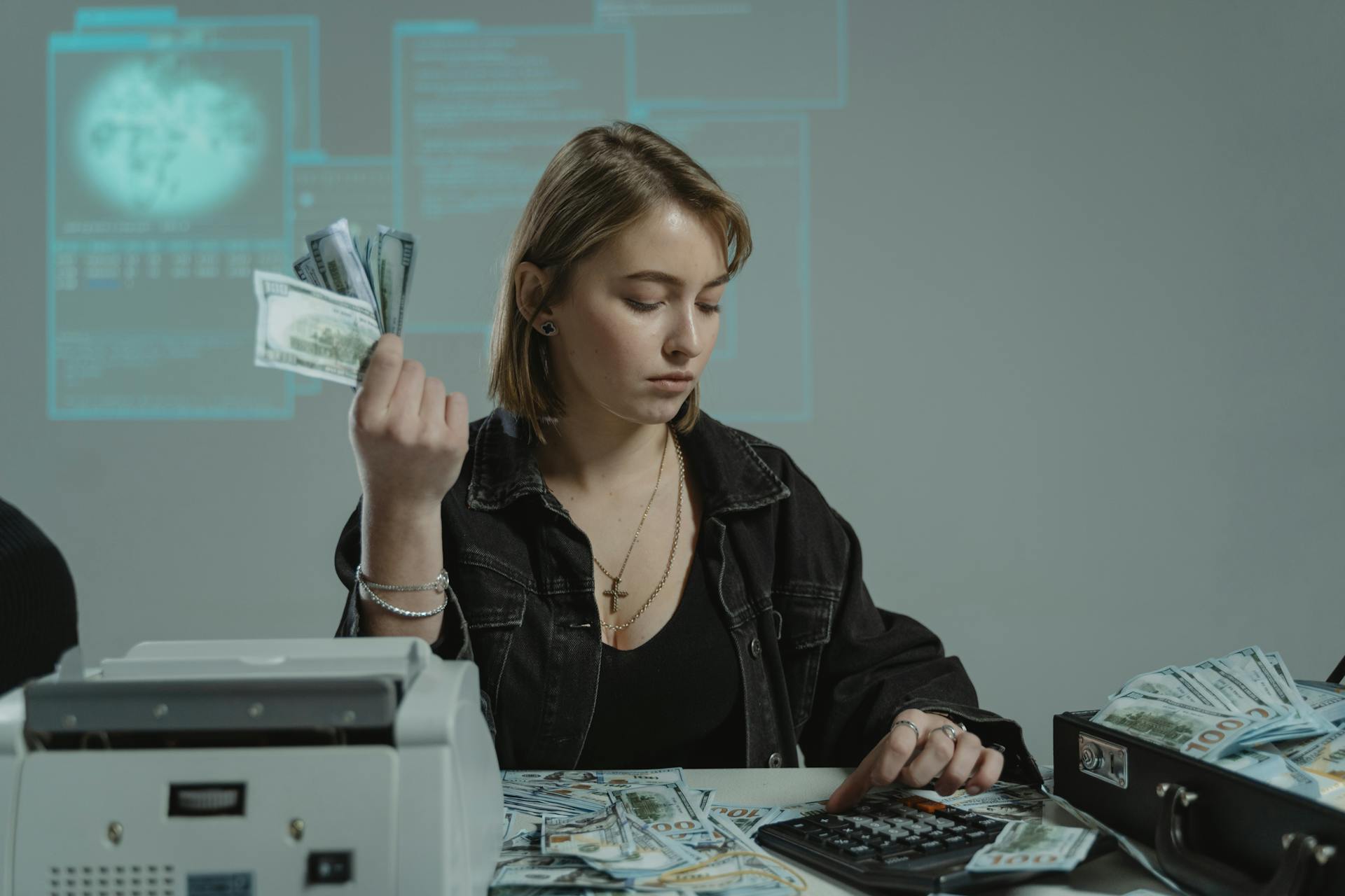 A Woman Sitting at a Table Accounting a Sum of Cash