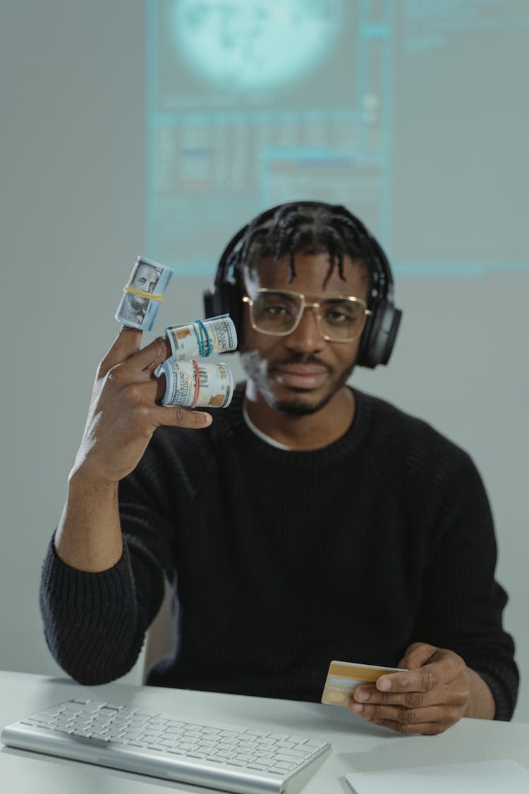 A Man In Black Sweater With Rolled Cash Inserted In His Fingers