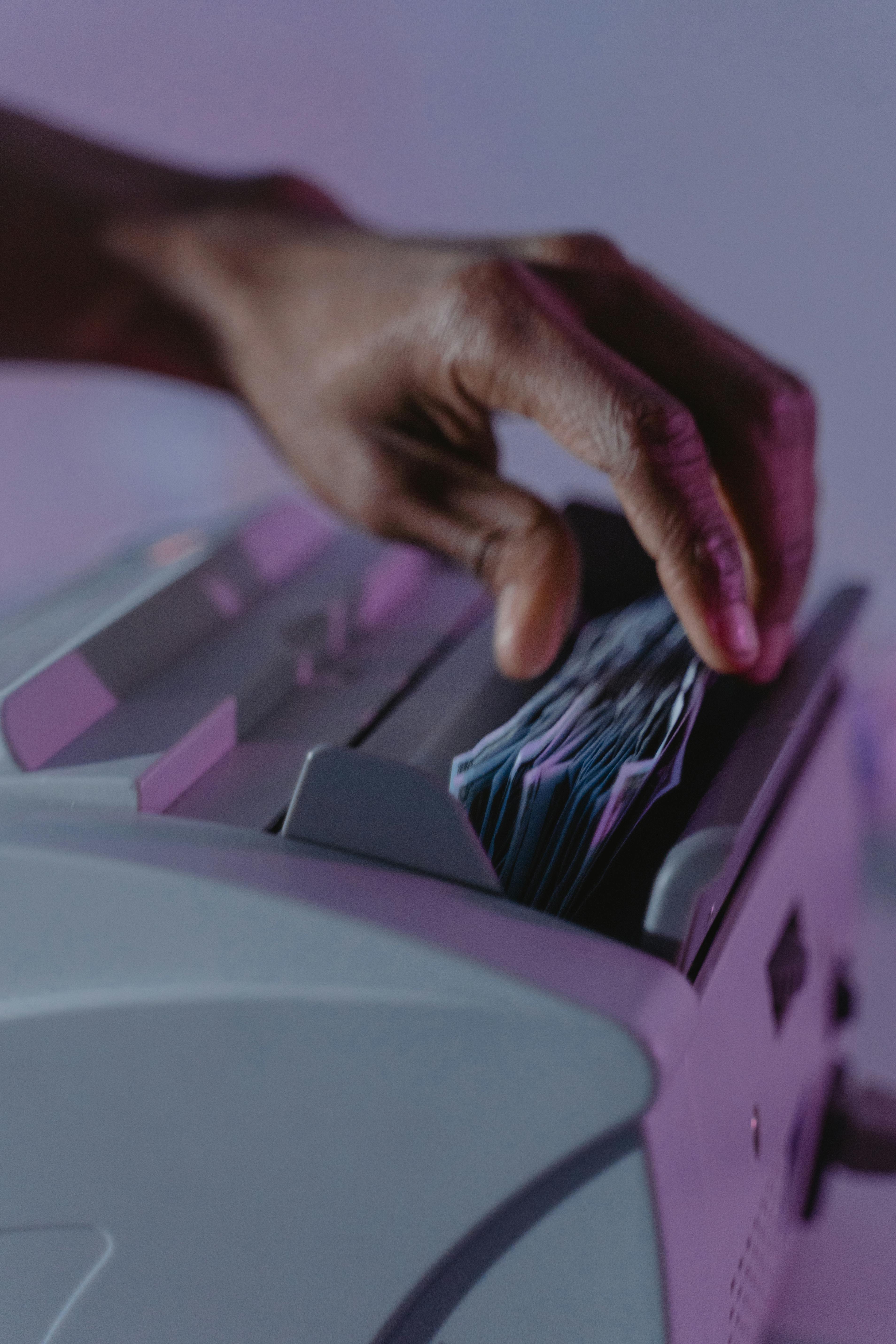 a person getting money bills from a money counter