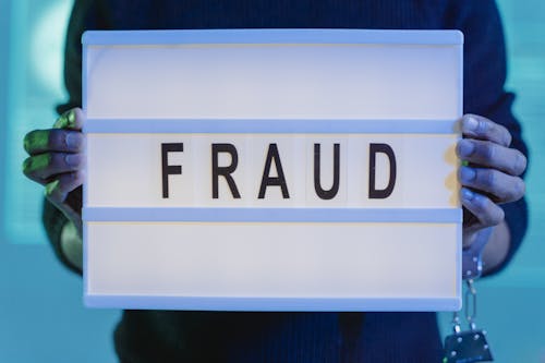 Free A Person with Handcuffs Holding a Sign that Says Fraud Stock Photo