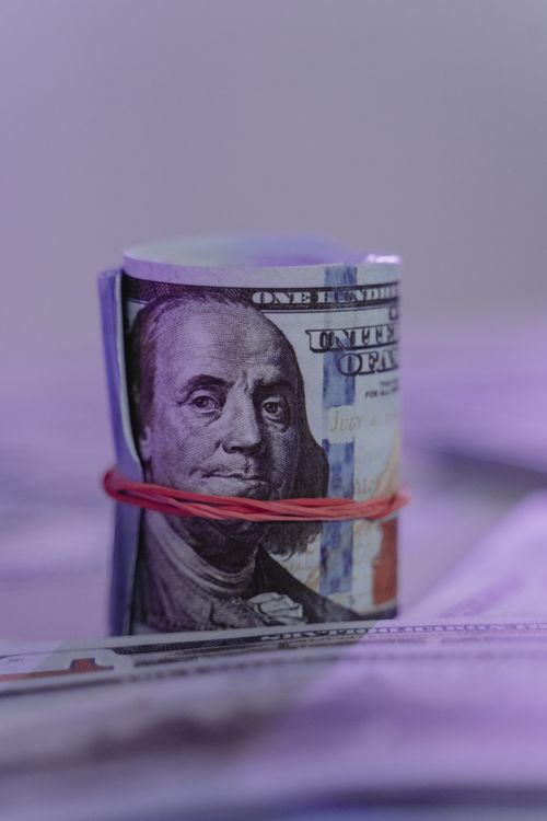 Free Close-up image of a rolled US dollar bill secured with a rubber band, creating an abstract financial concept. Stock Photo