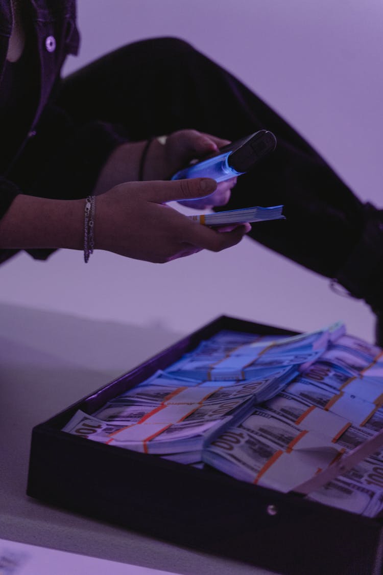 A Person Using UV Light On Money