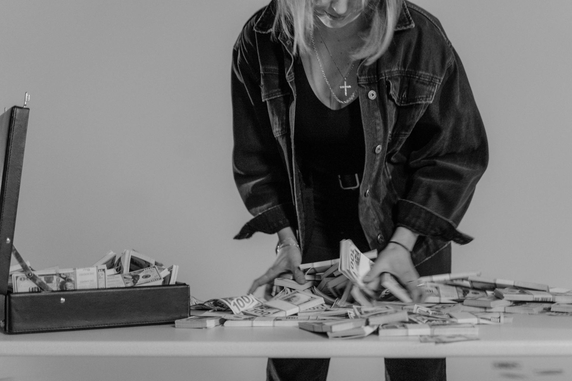 Monochrome Photo of Person Holding Bundles of Cash Money