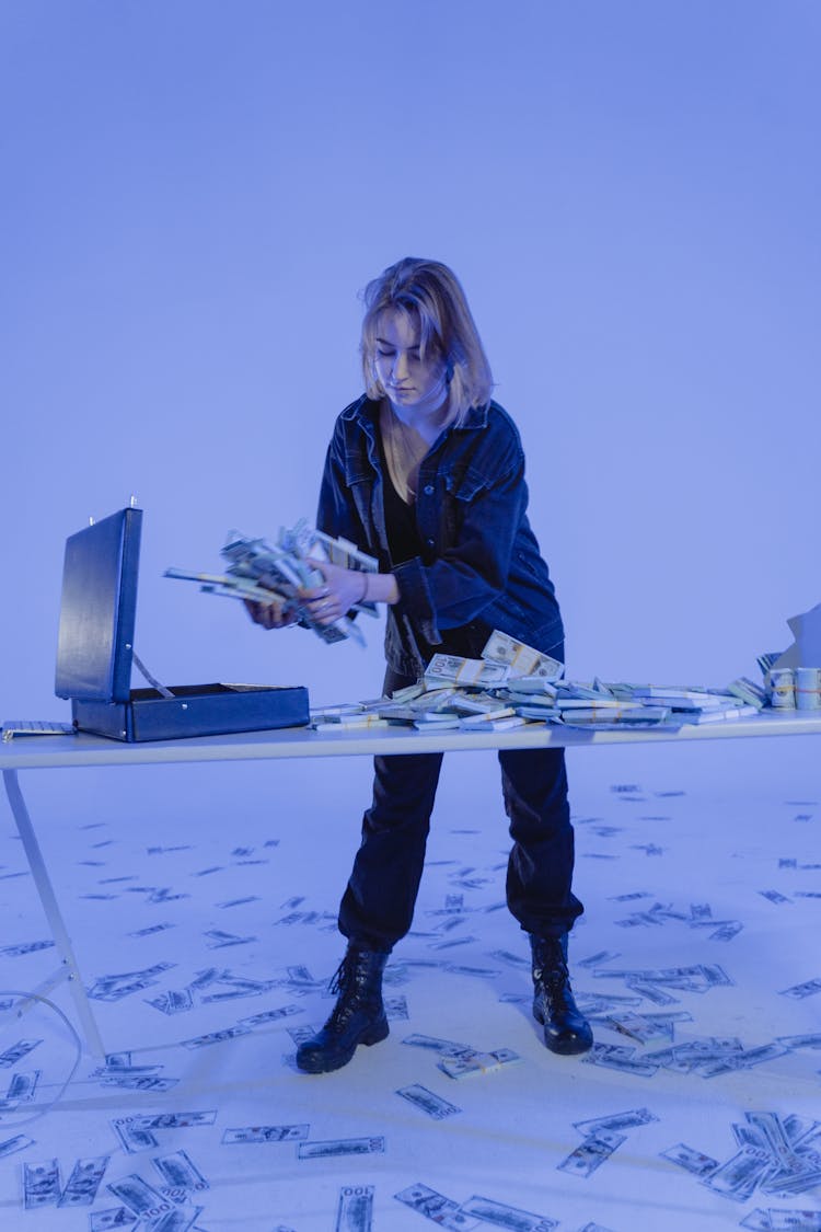 A Woman In A Denim Jacket Holding A Bundles Of Money