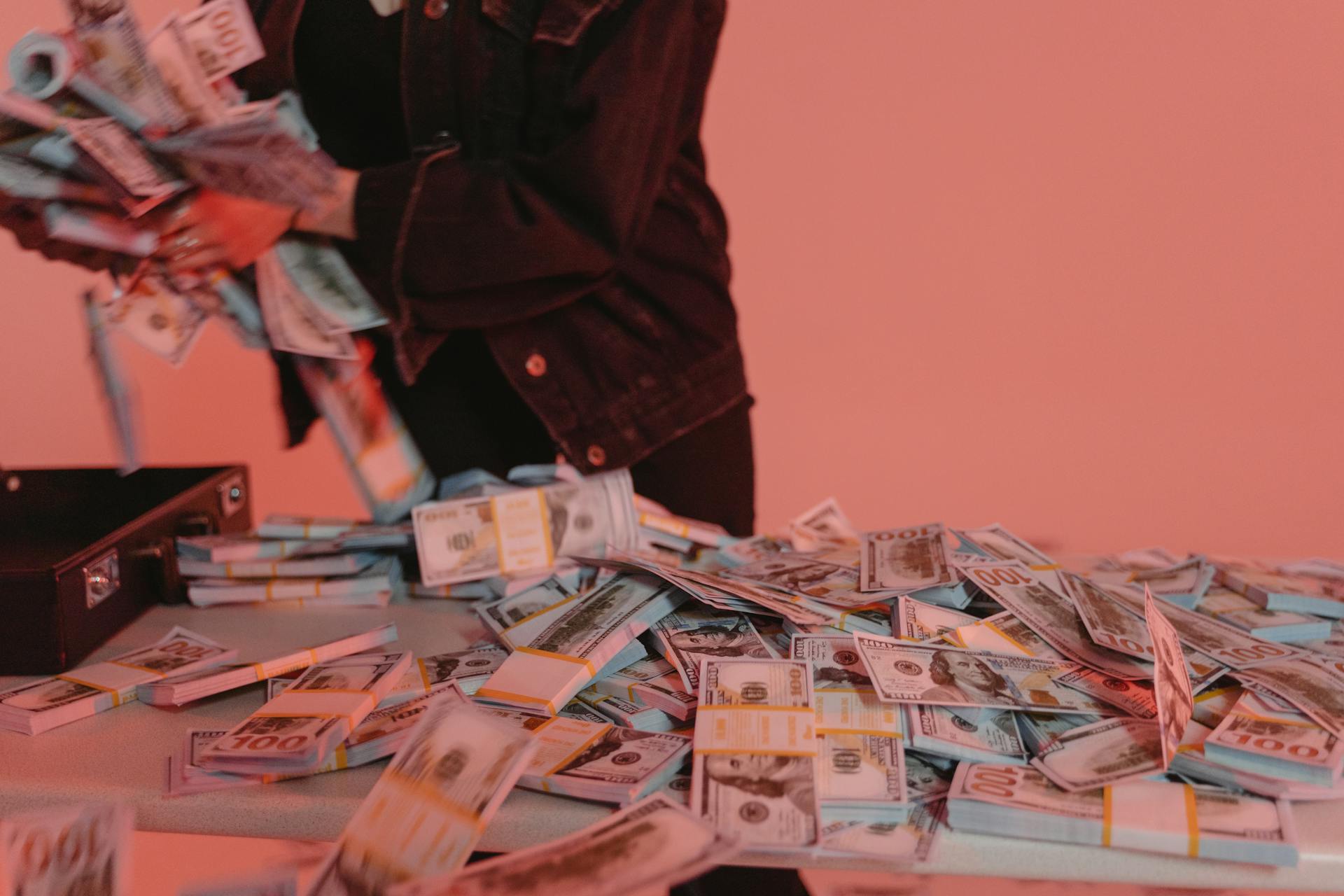 Bundles of US dollar bills on a table with a person organizing them.