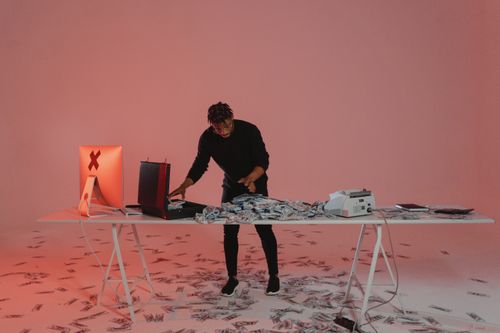 Free An individual processes piles of cash in a dimly lit room with a computer. Stock Photo